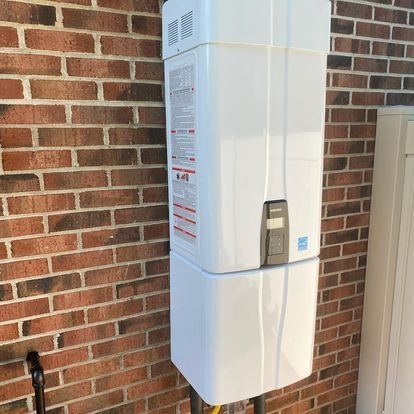 White tankless water heater on a brick wall.