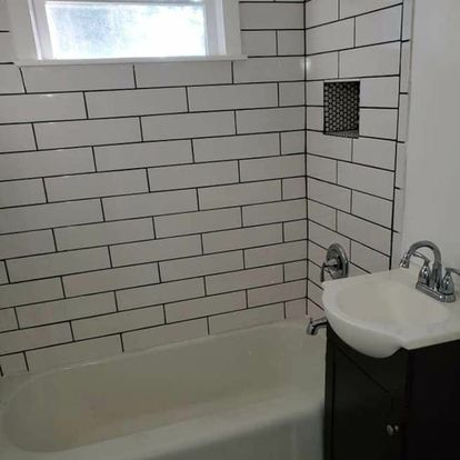 Bathroom with white subway tile, a bathtub, and a sink.