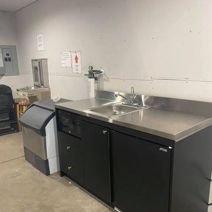 Commercial kitchen with stainless steel sink, black cabinets, and an ice machine.