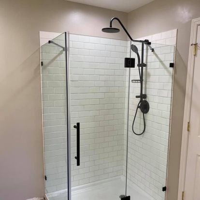 Modern shower stall with black fixtures and white subway tile. Clear glass doors and a rainfall showerhead.