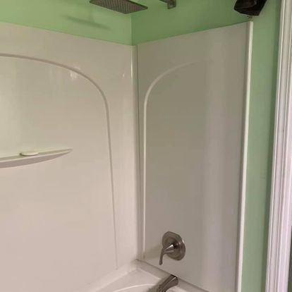 White shower stall in a bathroom with a green wall.