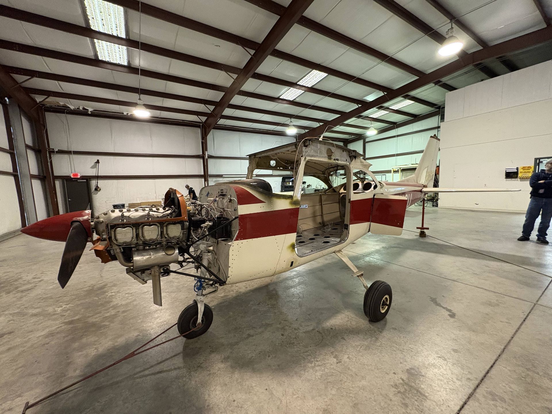 A small red and white plane is parked in a hangar
