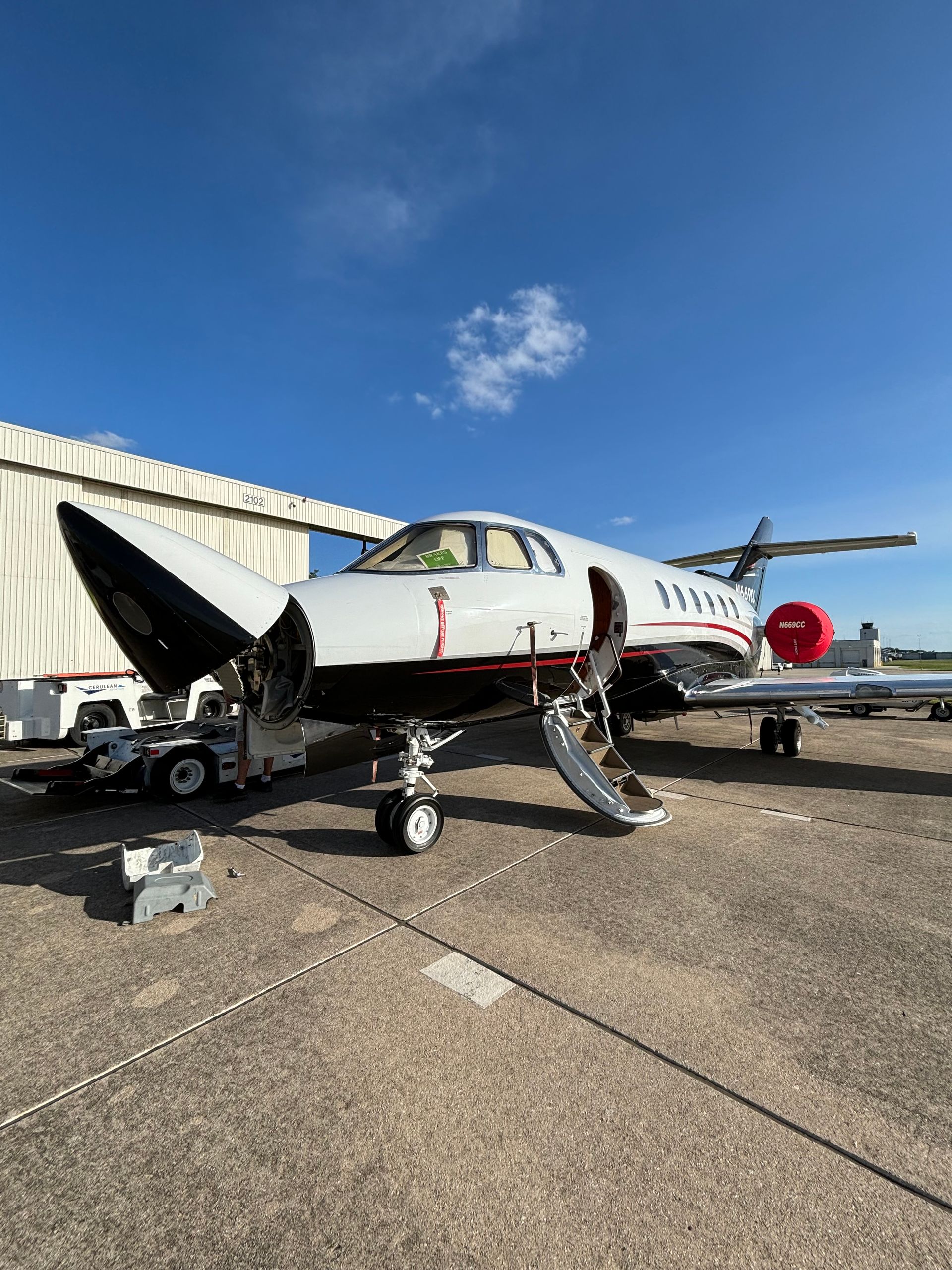 A small private jet is parked on the tarmac at an airport.