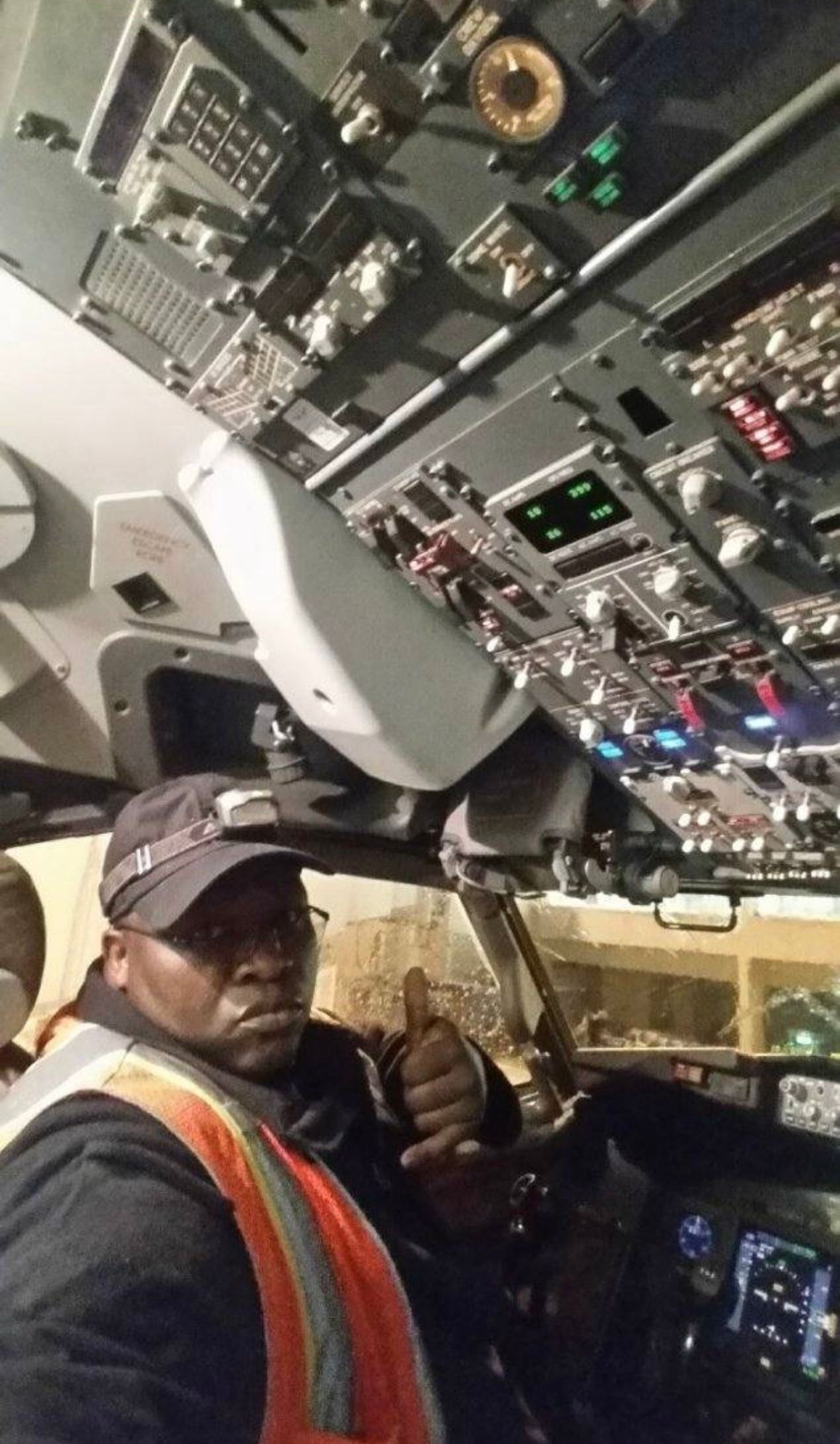 A man is sitting in the cockpit of an airplane giving a thumbs up.