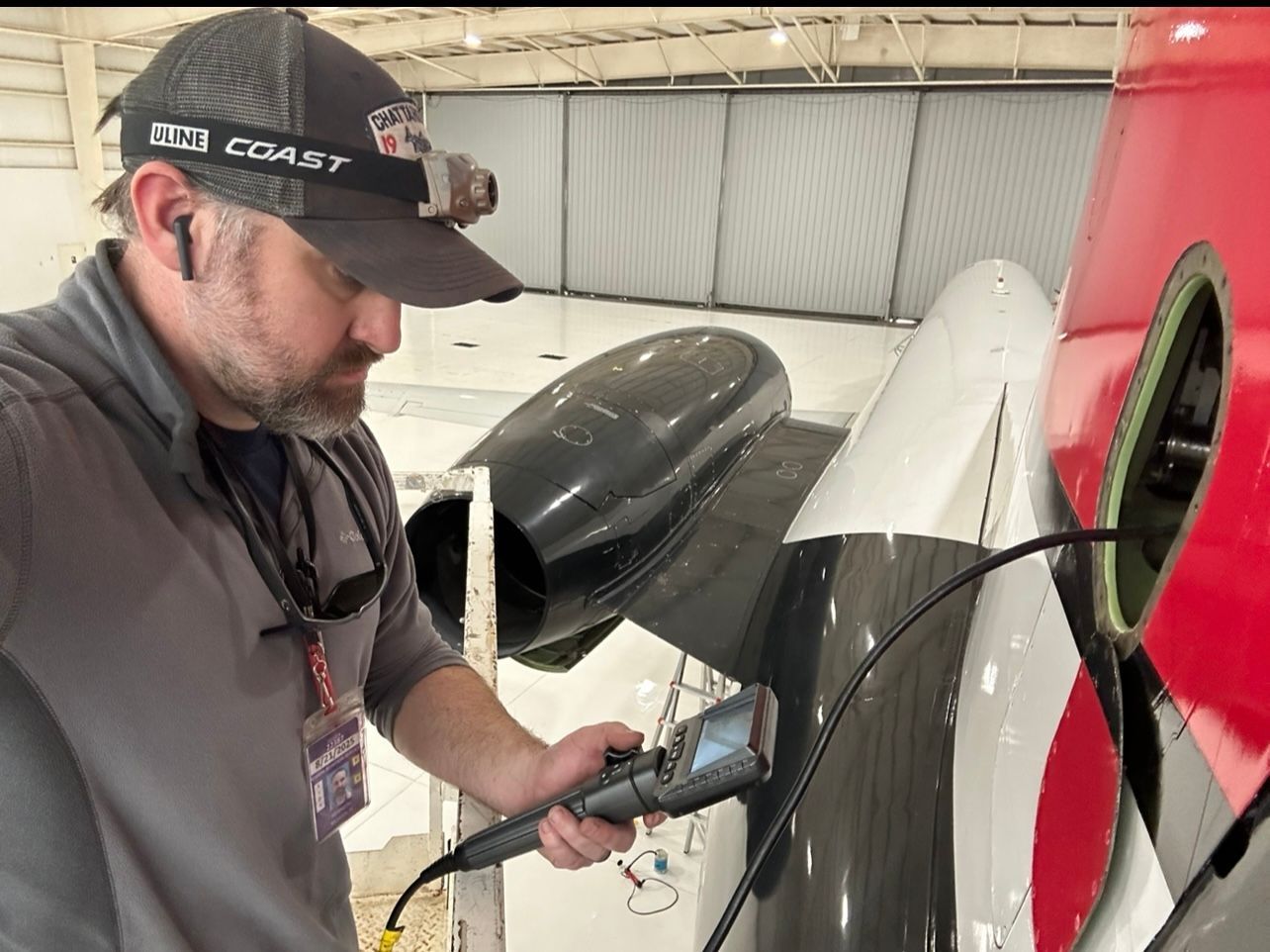 A man in a hat is working on an airplane in a hangar.