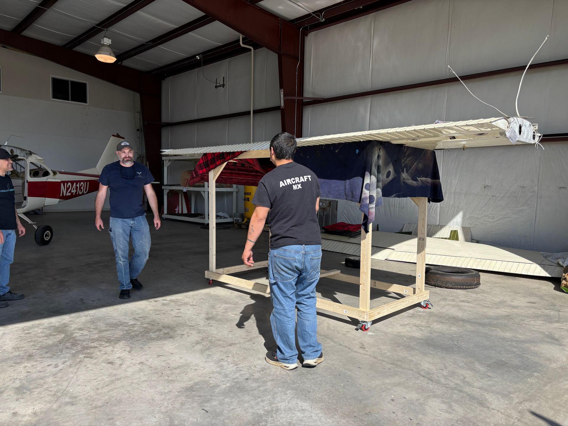 A man in a black shirt is standing in front of a small airplane.