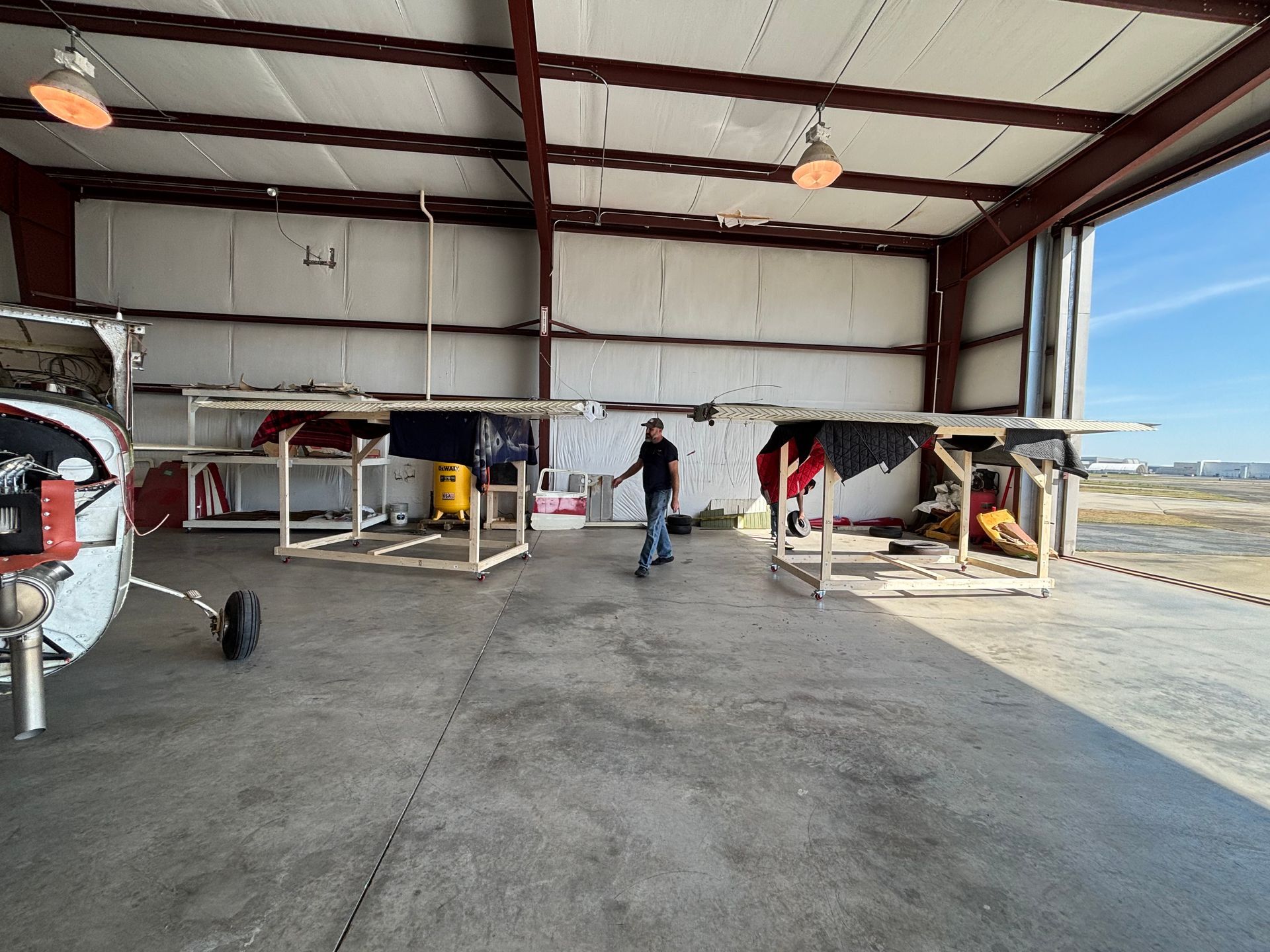 A man is standing in a hangar next to a plane.