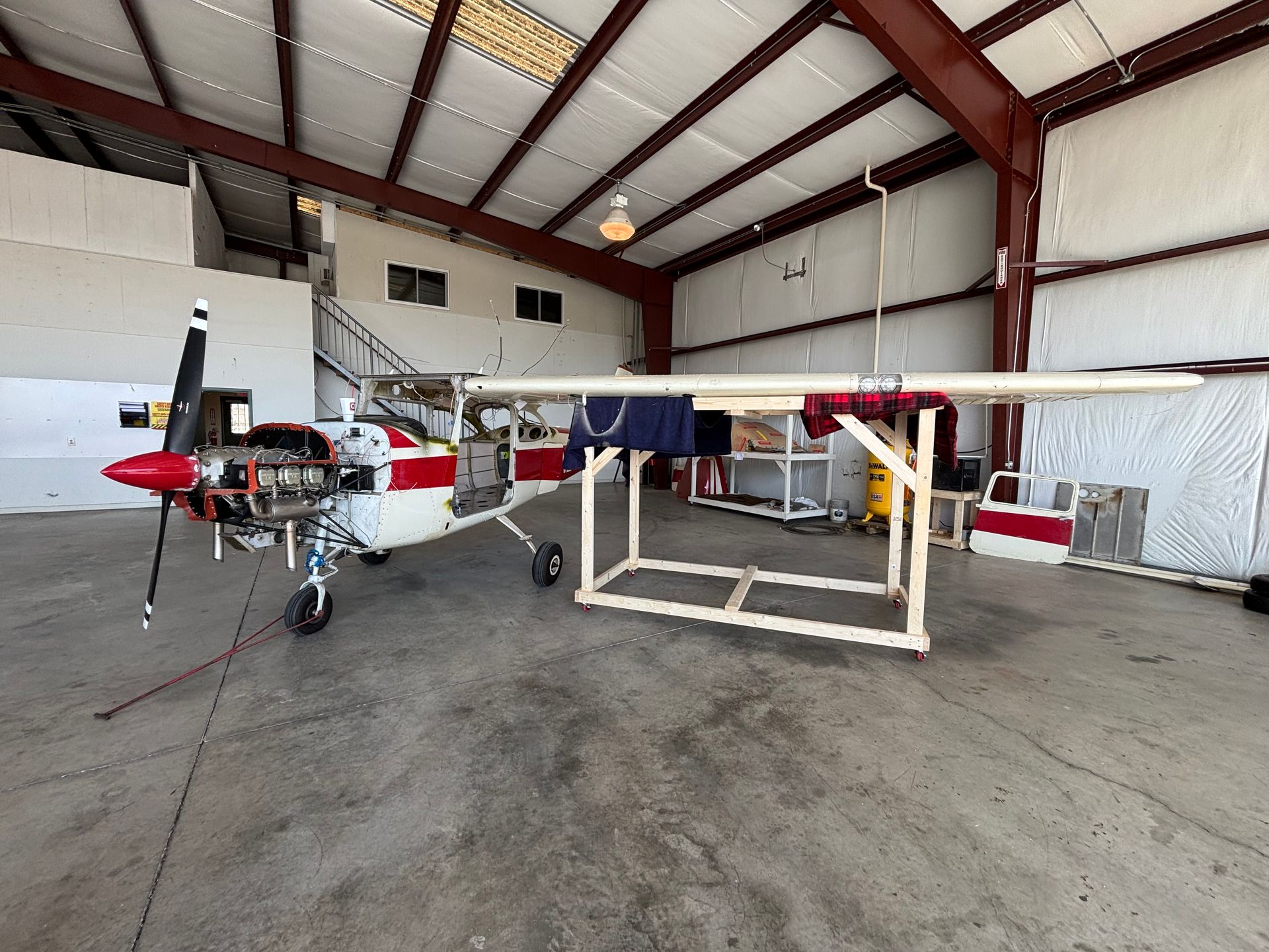 A small red and white plane is parked in a hangar