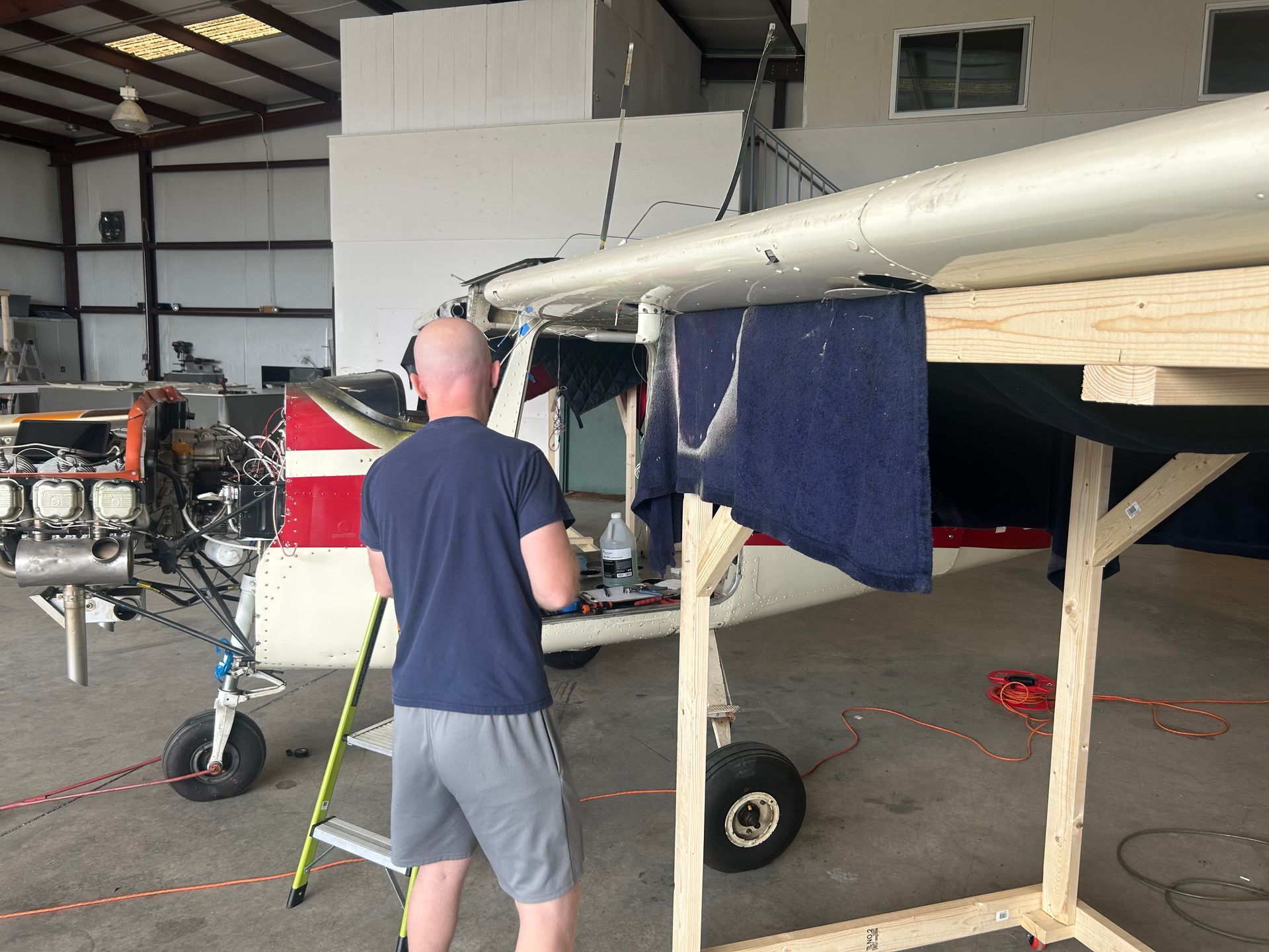 A man is working on a small plane in a hangar.