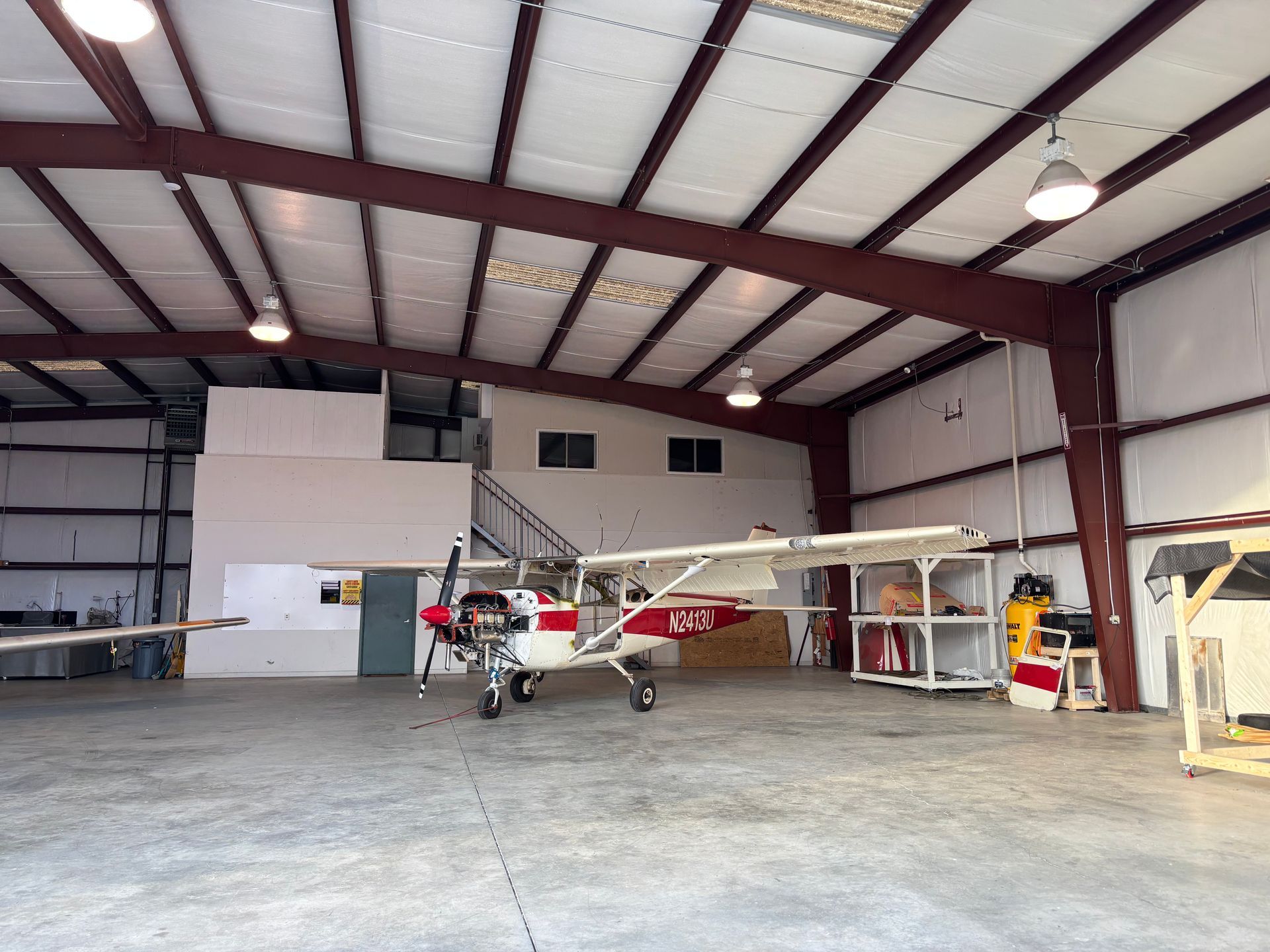 A small red and white plane is parked in a hangar