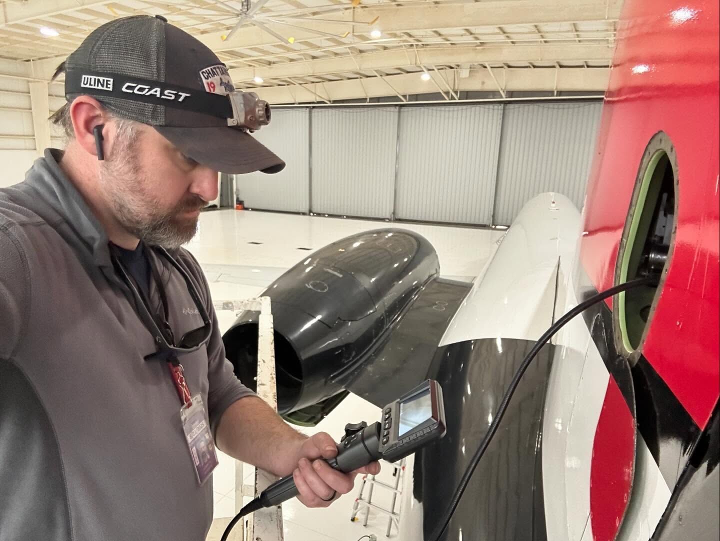 A man is working on an airplane in a hangar.