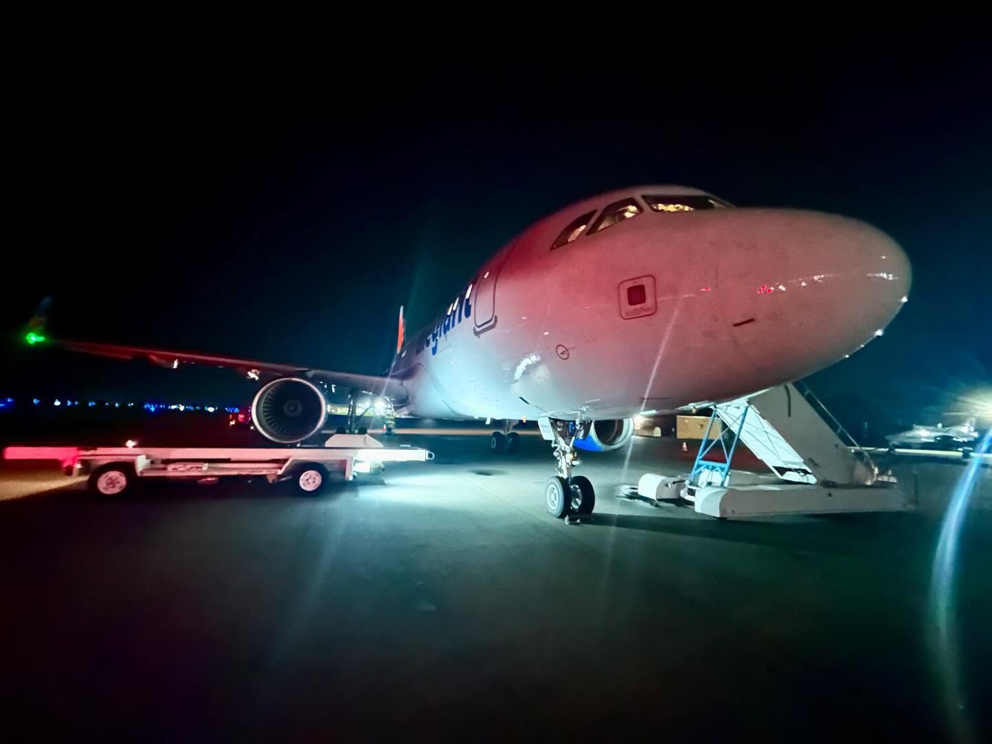 A large passenger jet is parked on a runway at night.