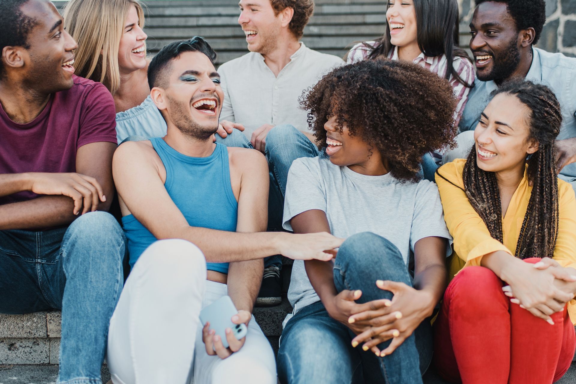 A group of people are sitting on a set of stairs and laughing.