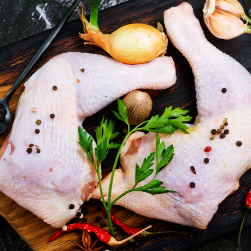 Raw chicken legs on a wooden cutting board with spices