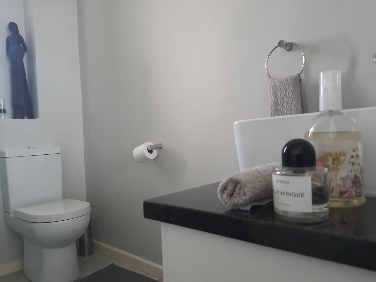 A bathroom with a toilet a sink and a bottle of perfume