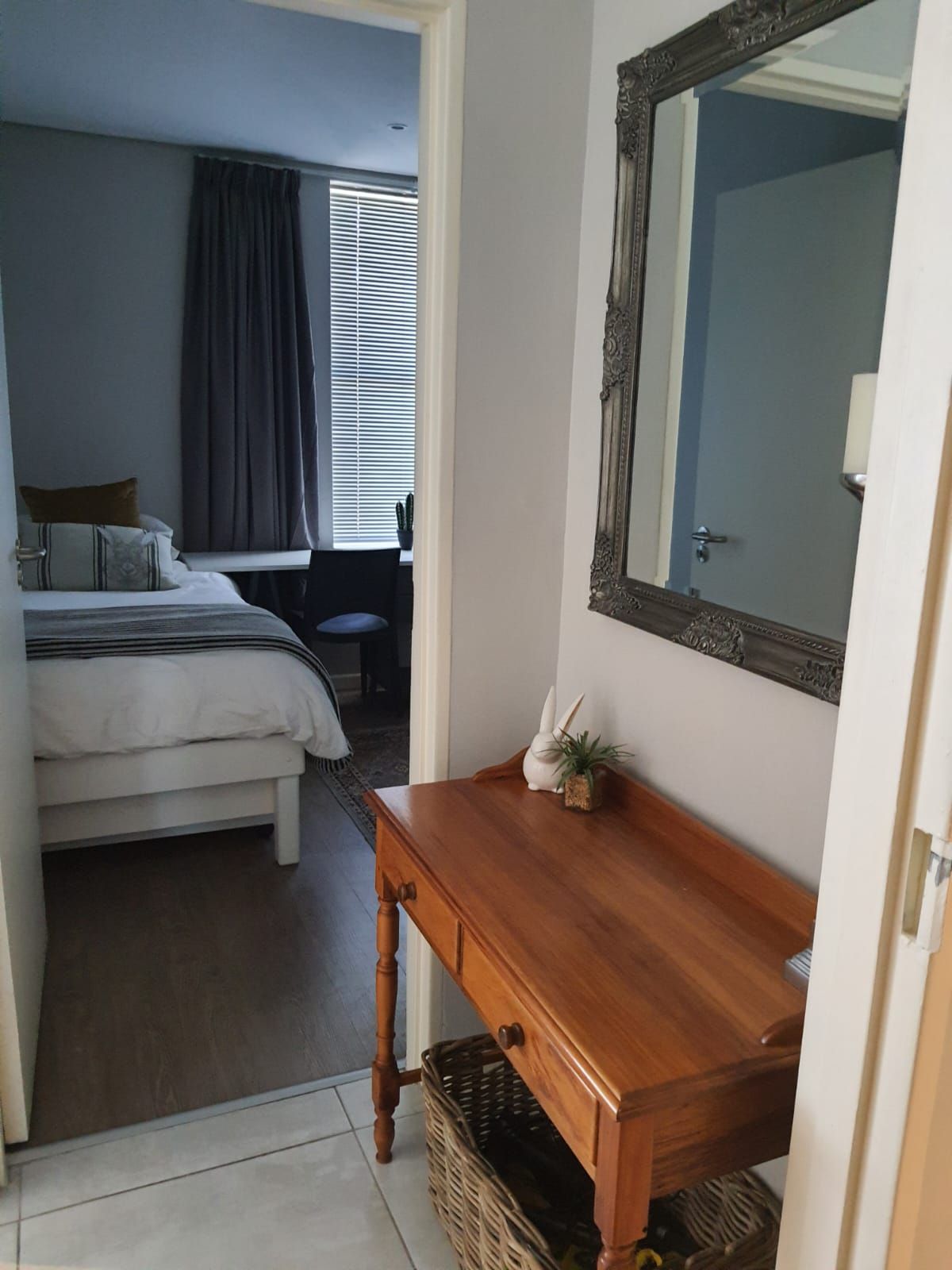 A bedroom with a wooden desk and a mirror.