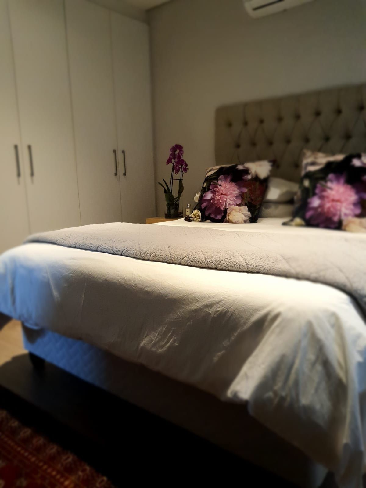 A bed with white sheets and purple pillows in a bedroom