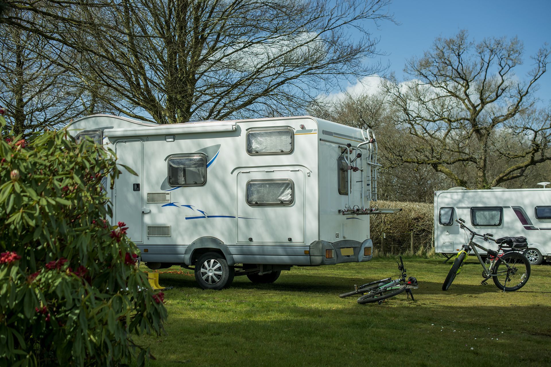 A white rv is parked in a grassy field next to a bicycle.