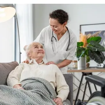 An elderly woman is sitting on a couch with a nurse standing next to her.