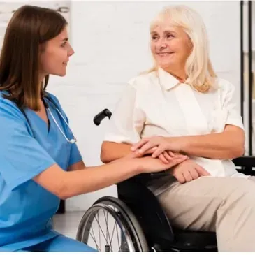 A nurse is talking to an older woman in a wheelchair