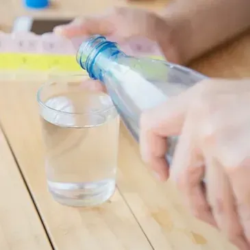 A person is pouring water from a bottle into a glass.