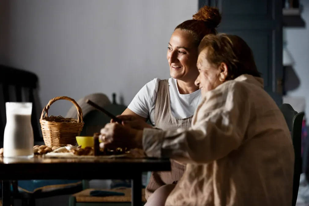 A woman is sitting at a table with an older woman.
