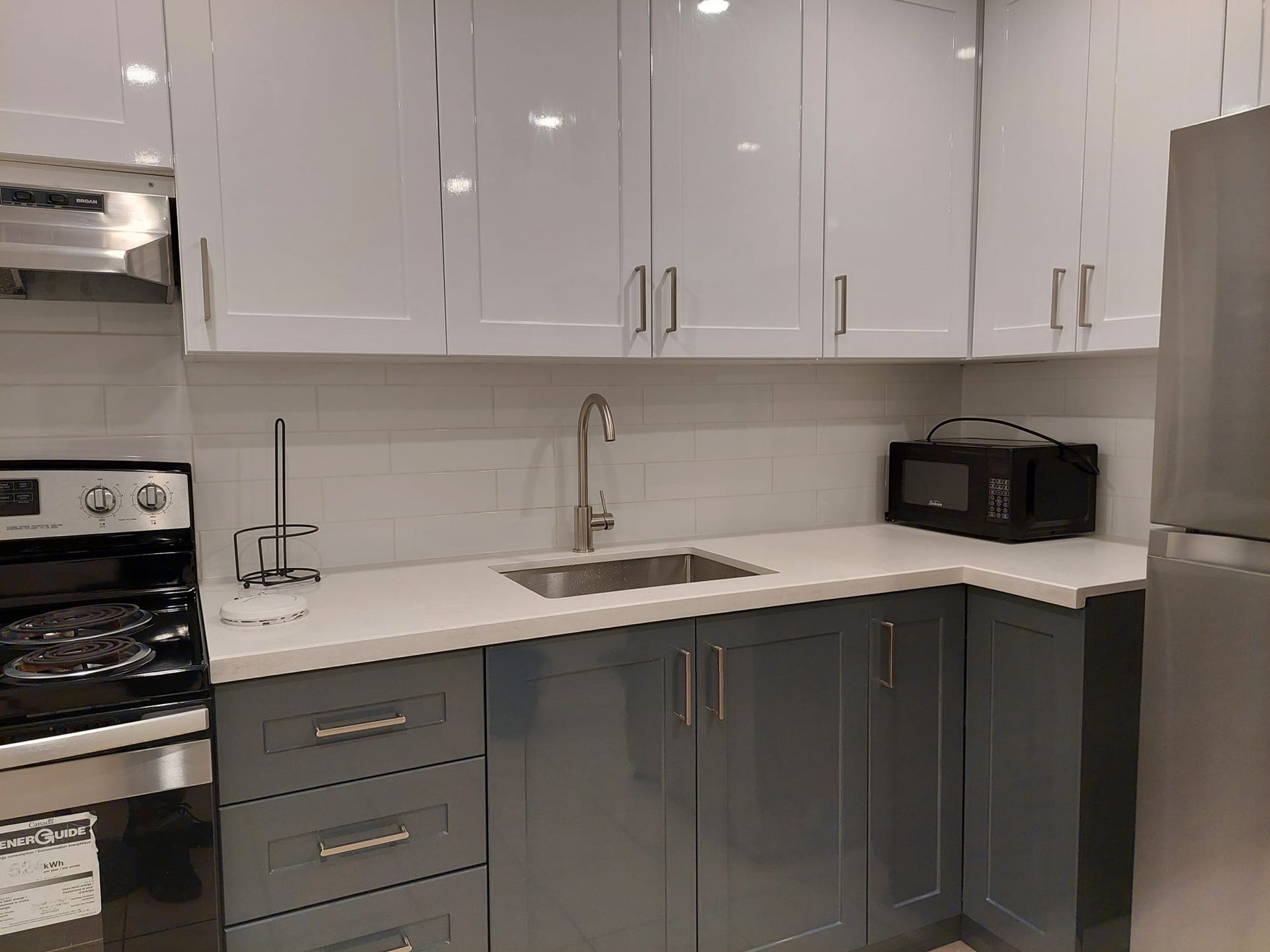 A kitchen with a sink , stove , refrigerator and microwave.