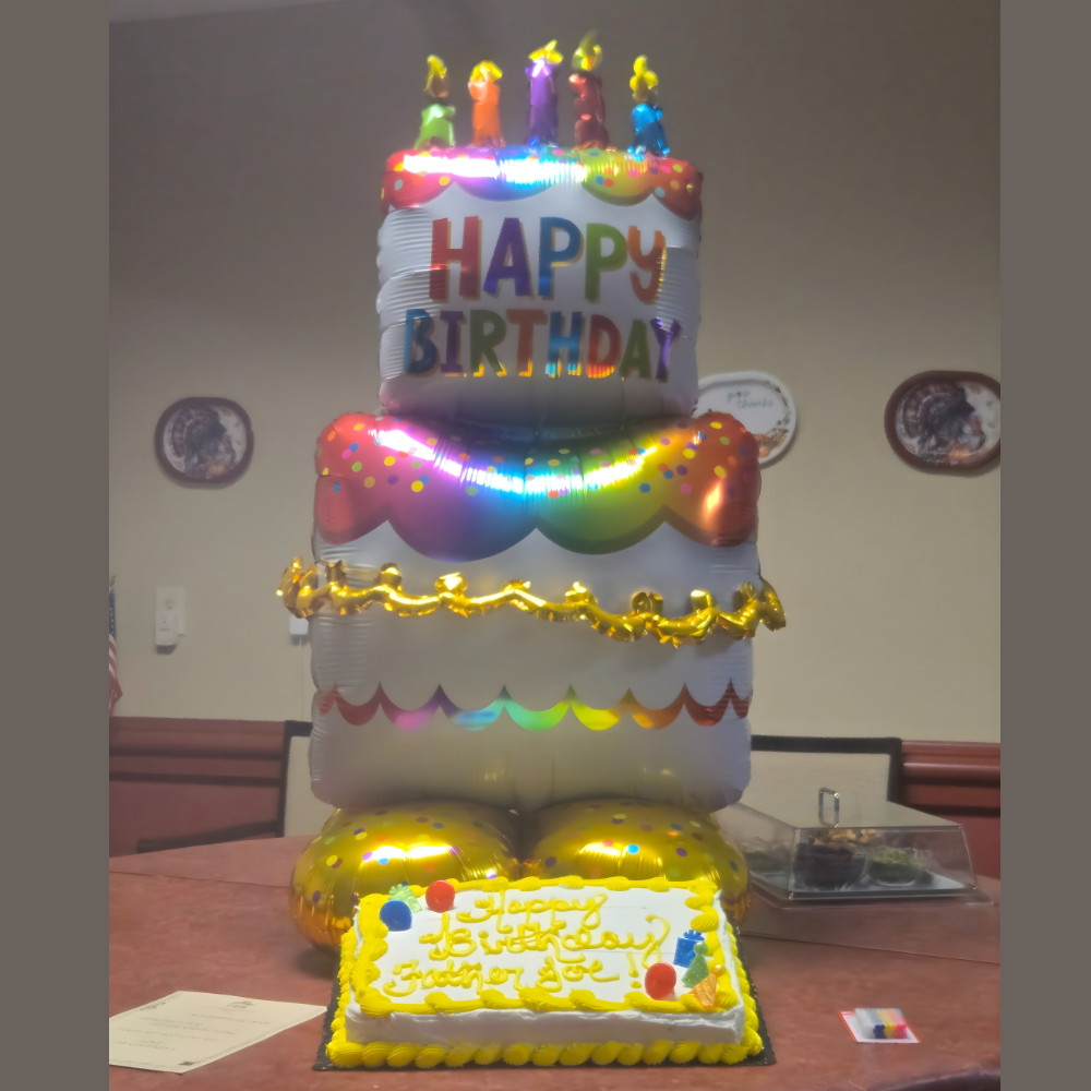Birthday cake balloon decoration and yellow cake on a table.