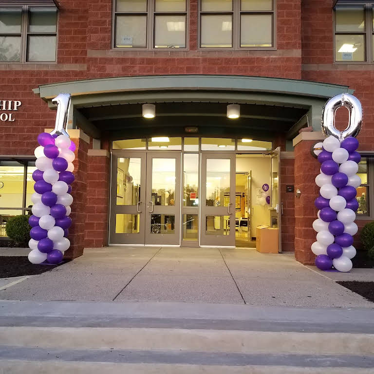 A brick building with purple and white balloons in front of it