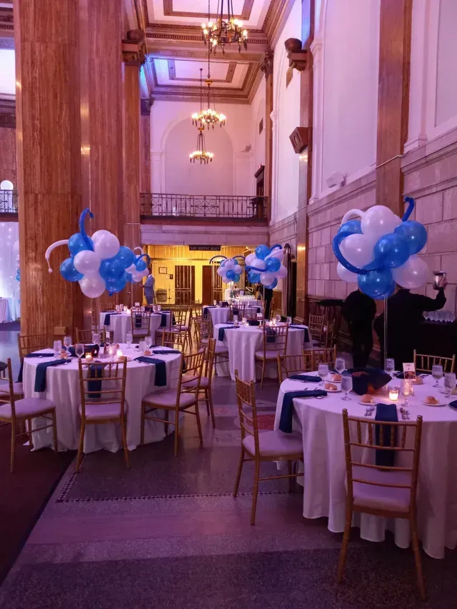 A large room with tables and chairs decorated with blue and white balloons