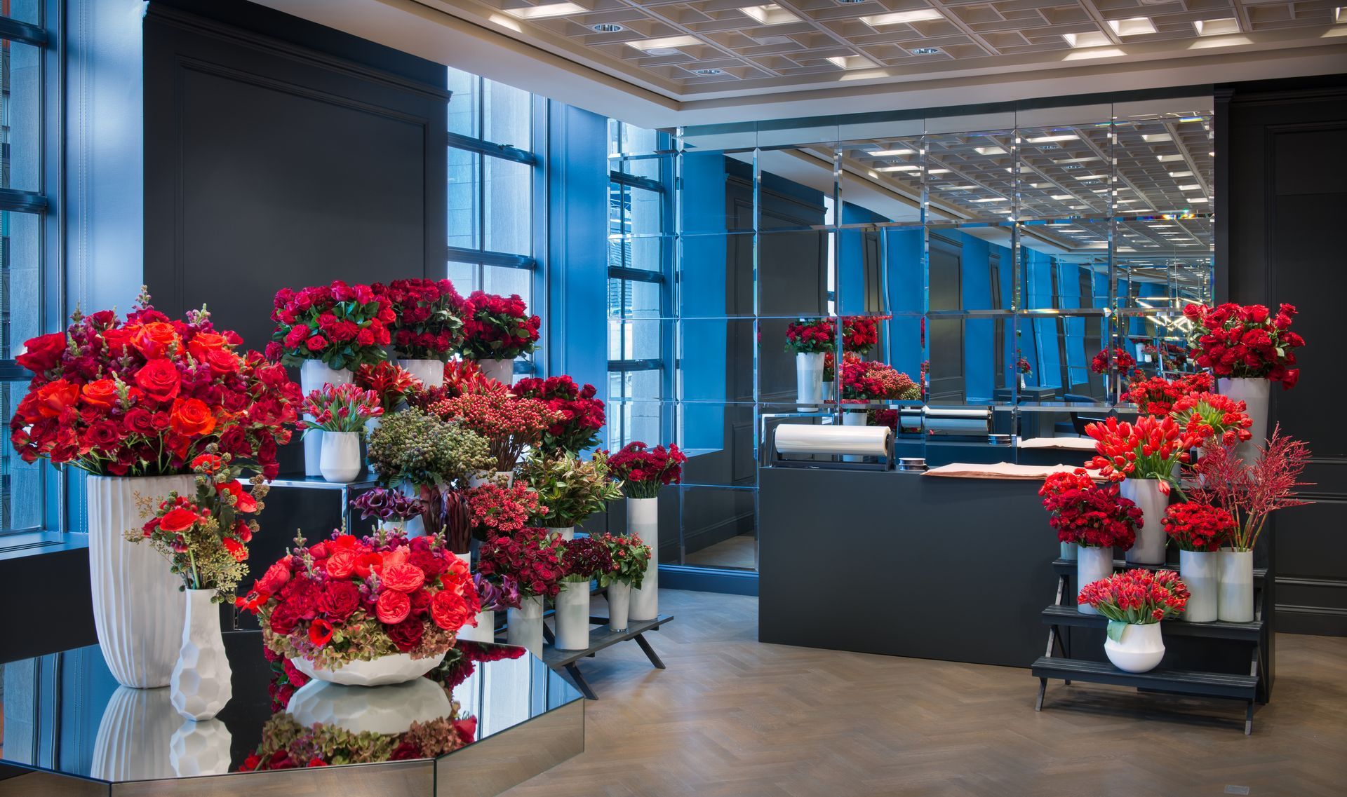 Modern office lobby with large red flower arrangements and blue glass walls