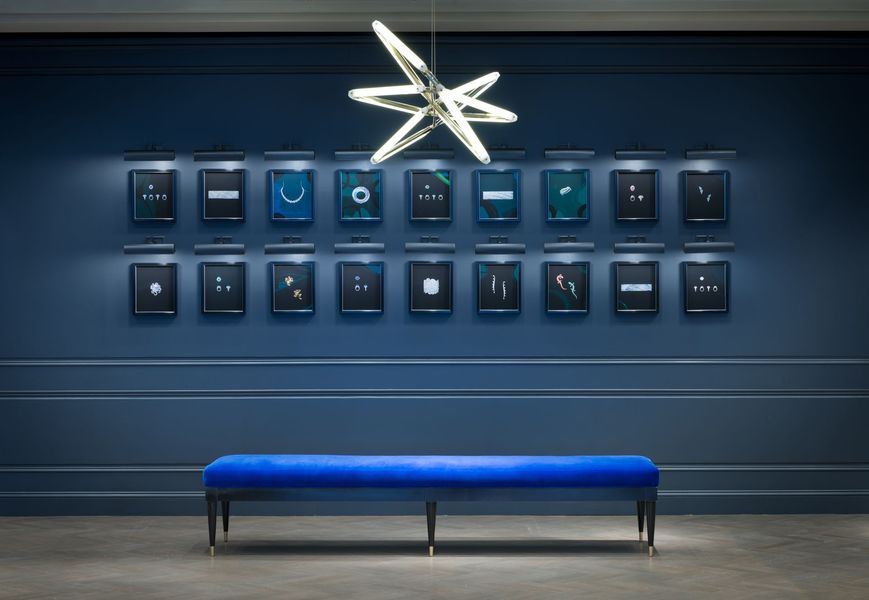 Blue bench beneath a wall of framed art, lit by a star-shaped light in a modern gallery
