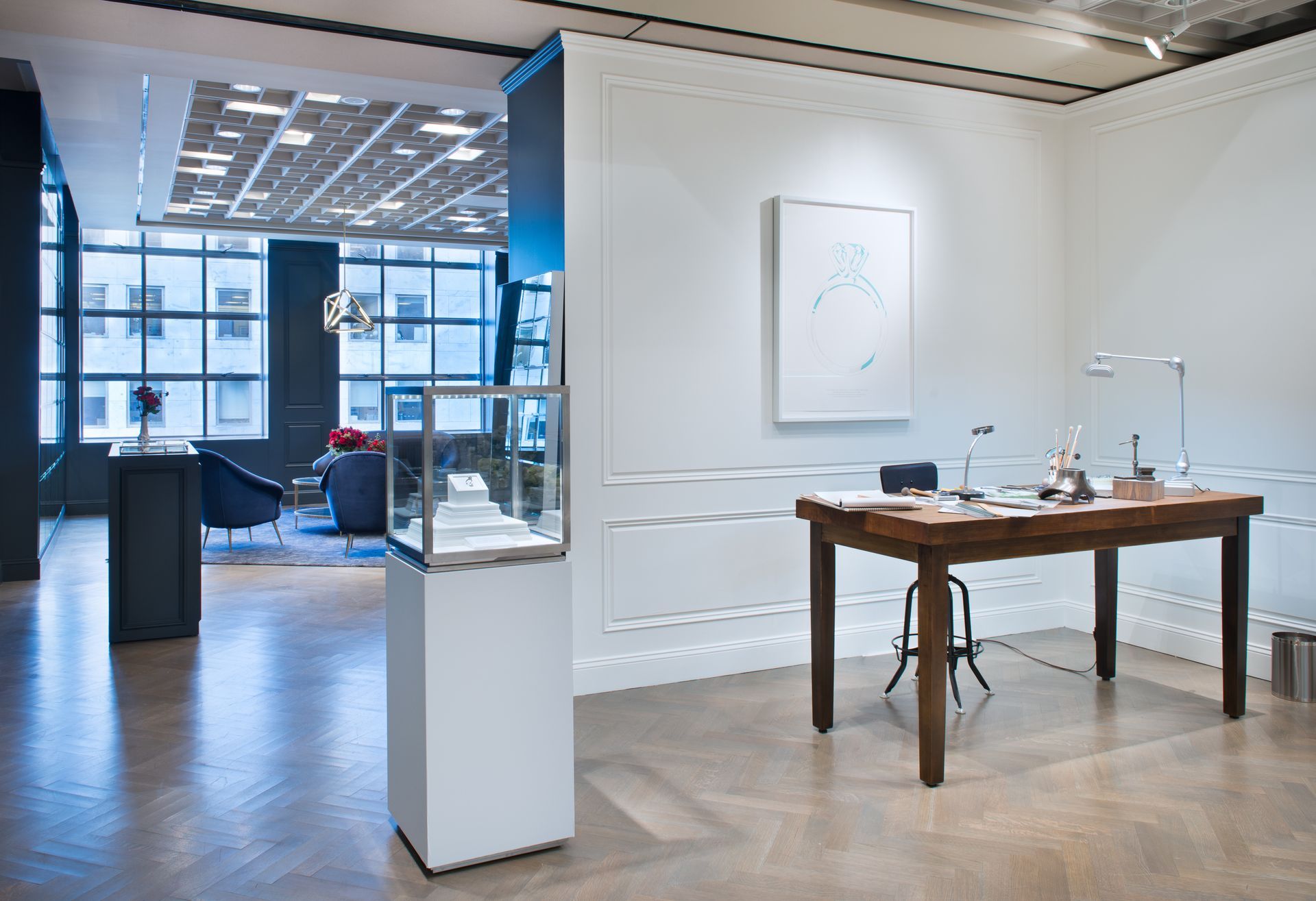 Modern art gallery with white walls, framed art, wooden table, and glass storefront entrance.