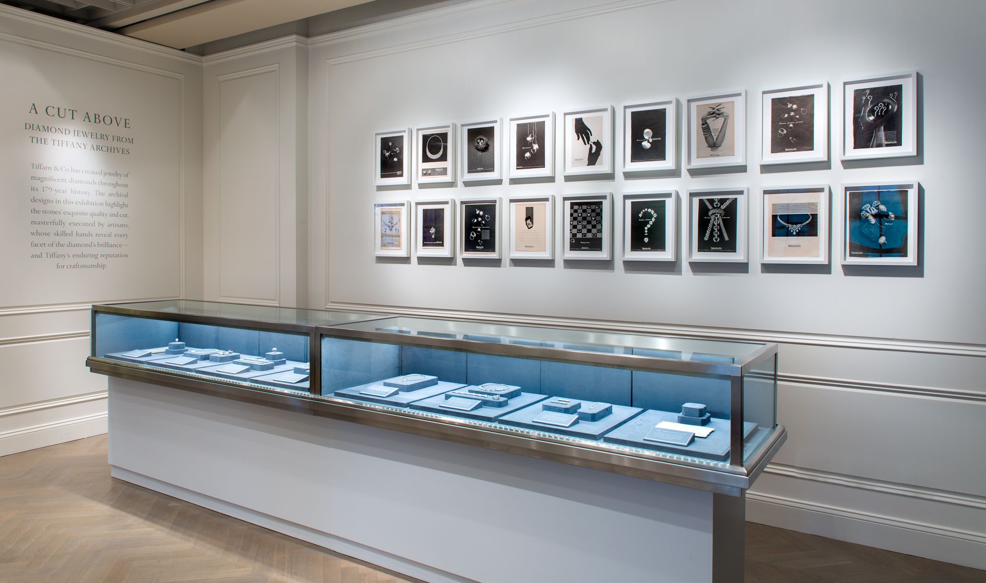 Gallery display of phones in glass case with framed photos on a white wall