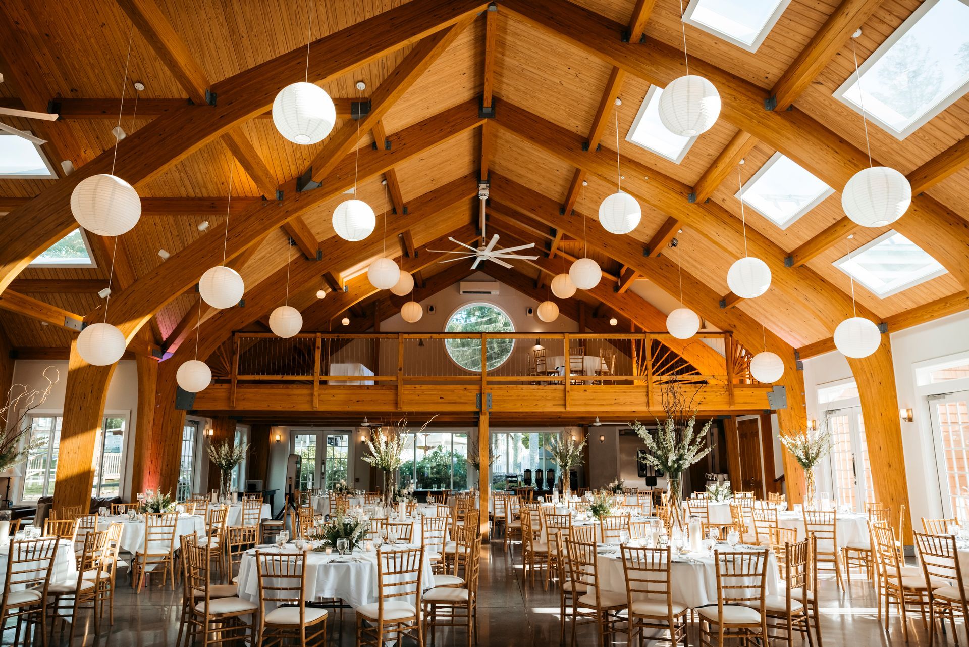 Elegant banquet hall with wooden beams, skylights, and round tables set for a reception
