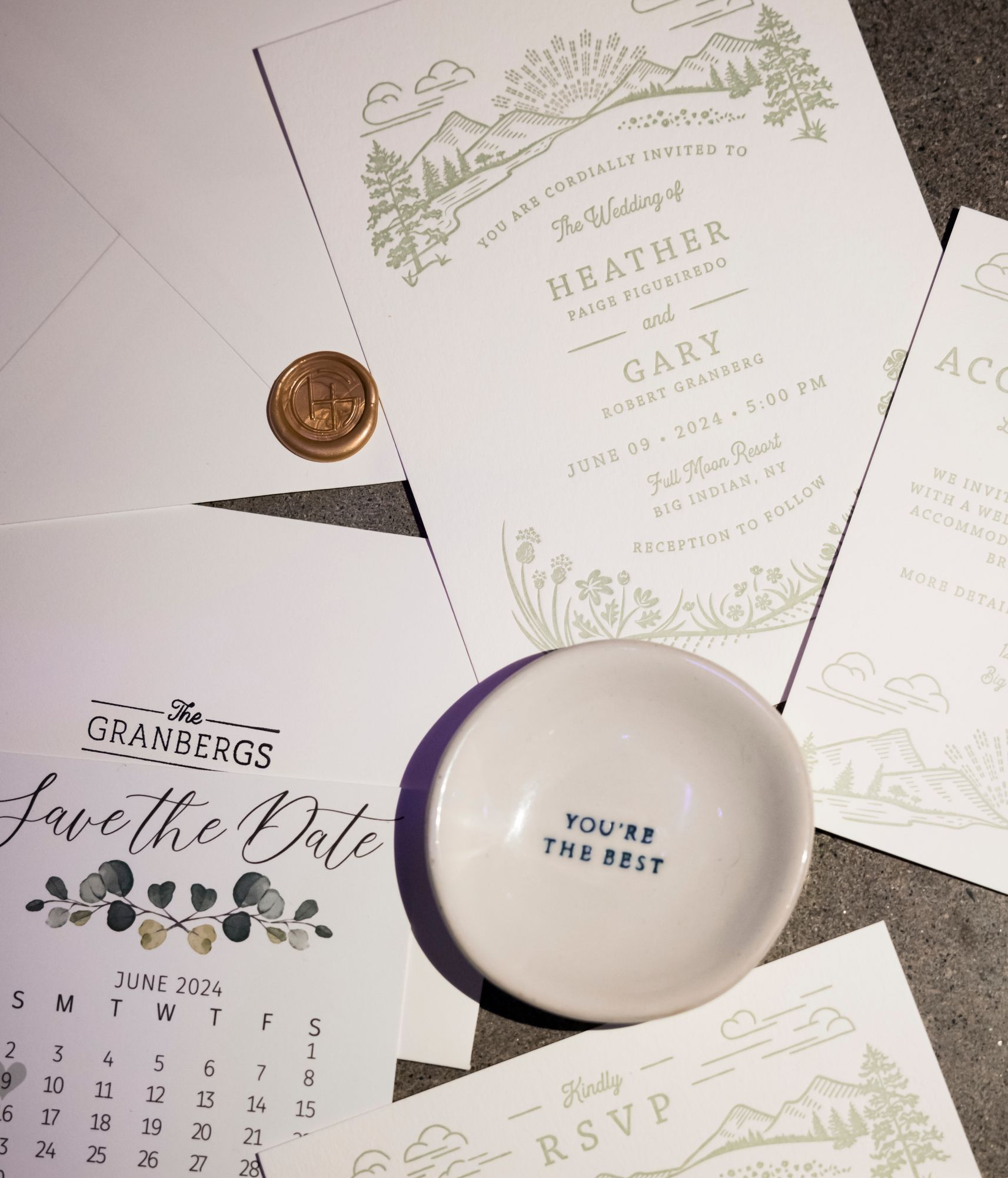 Elegant wedding stationery with white and green floral invitations, RSVP cards, a coin, and a candle holder.