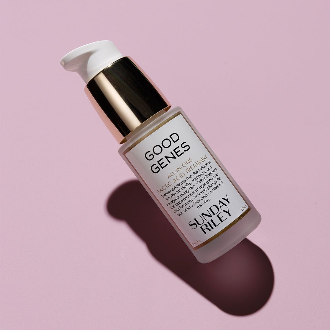 Tilting lotion bottle with white pump on pink background, labeled “Good Genes” and “Sunday Riley”