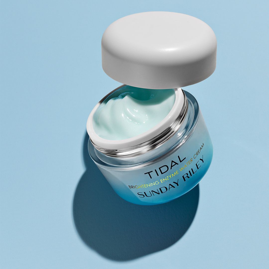 Open jar of turquoise cream with white lid on a light blue background