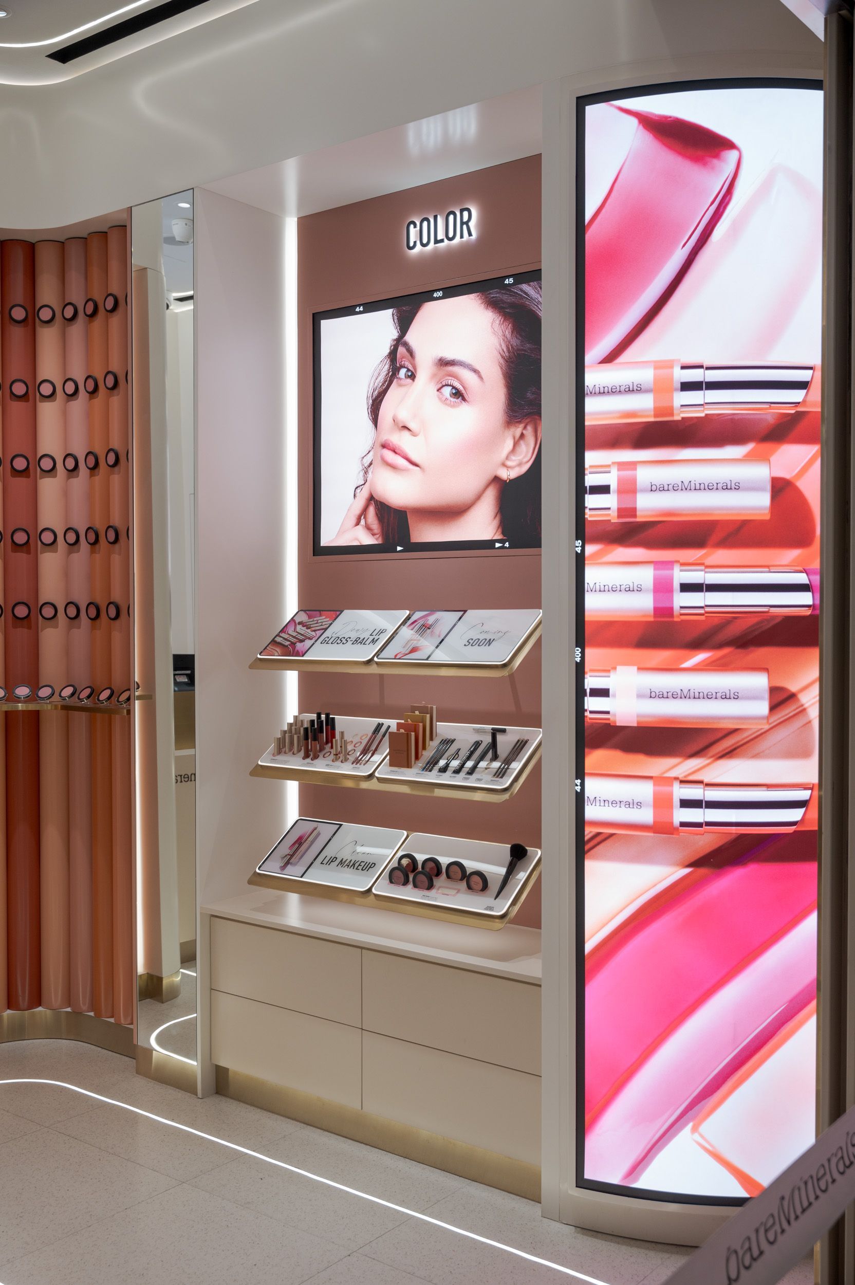 Luxury Dior makeup display with pink-lit shelves, product samples, and a portrait ad in a store