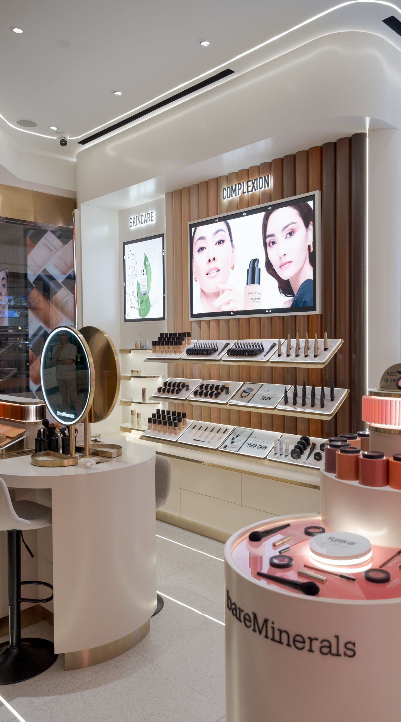 Cosmetics store display with makeup shelves, mirrors, and product posters in a bright, modern shop