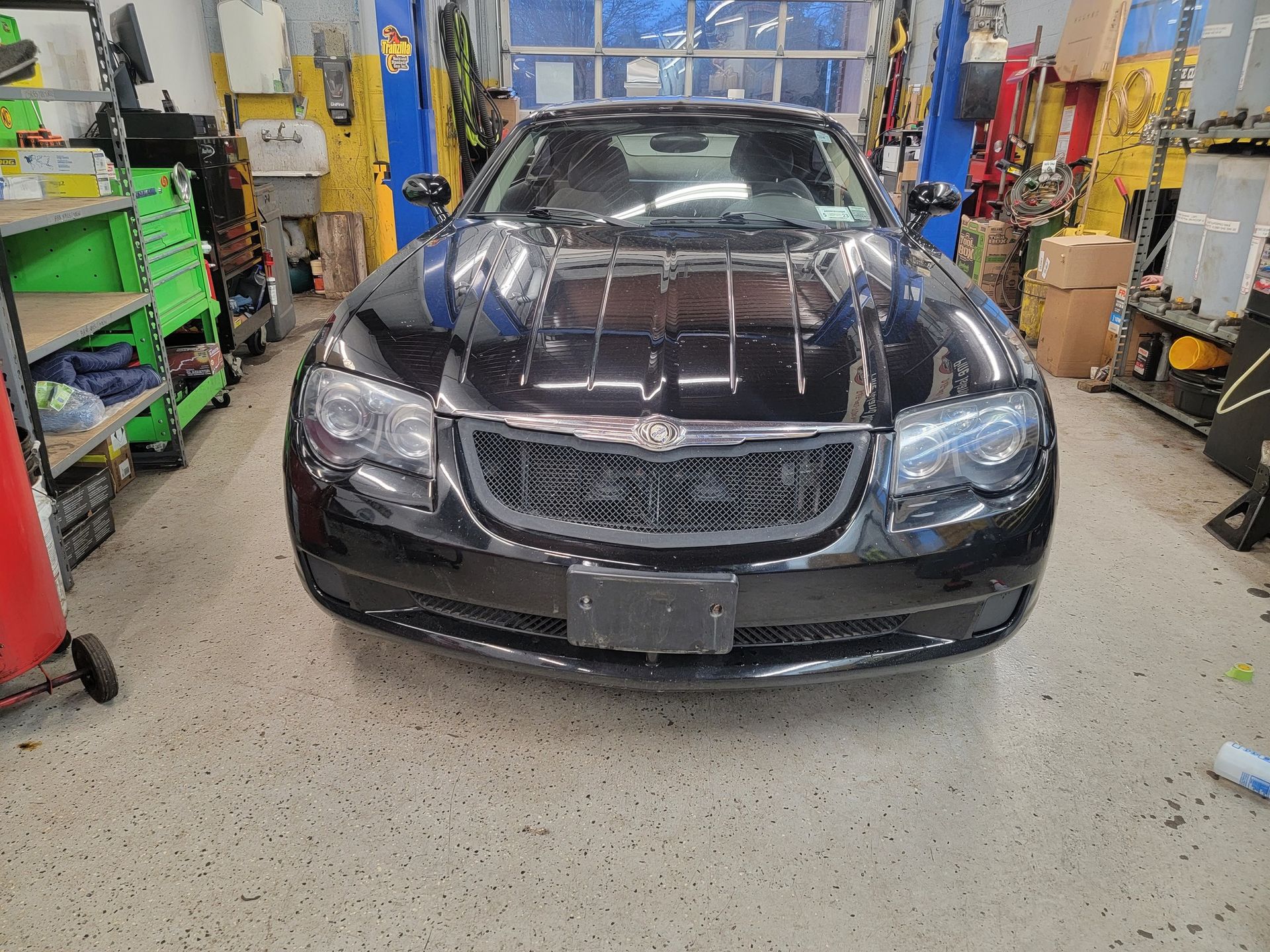 Black Chrysler 300 in a car repair shop, facing forward.