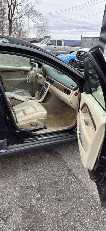 Interior of a car with beige leather seats and dashboard, featuring a light-colored steering wheel and door trim.