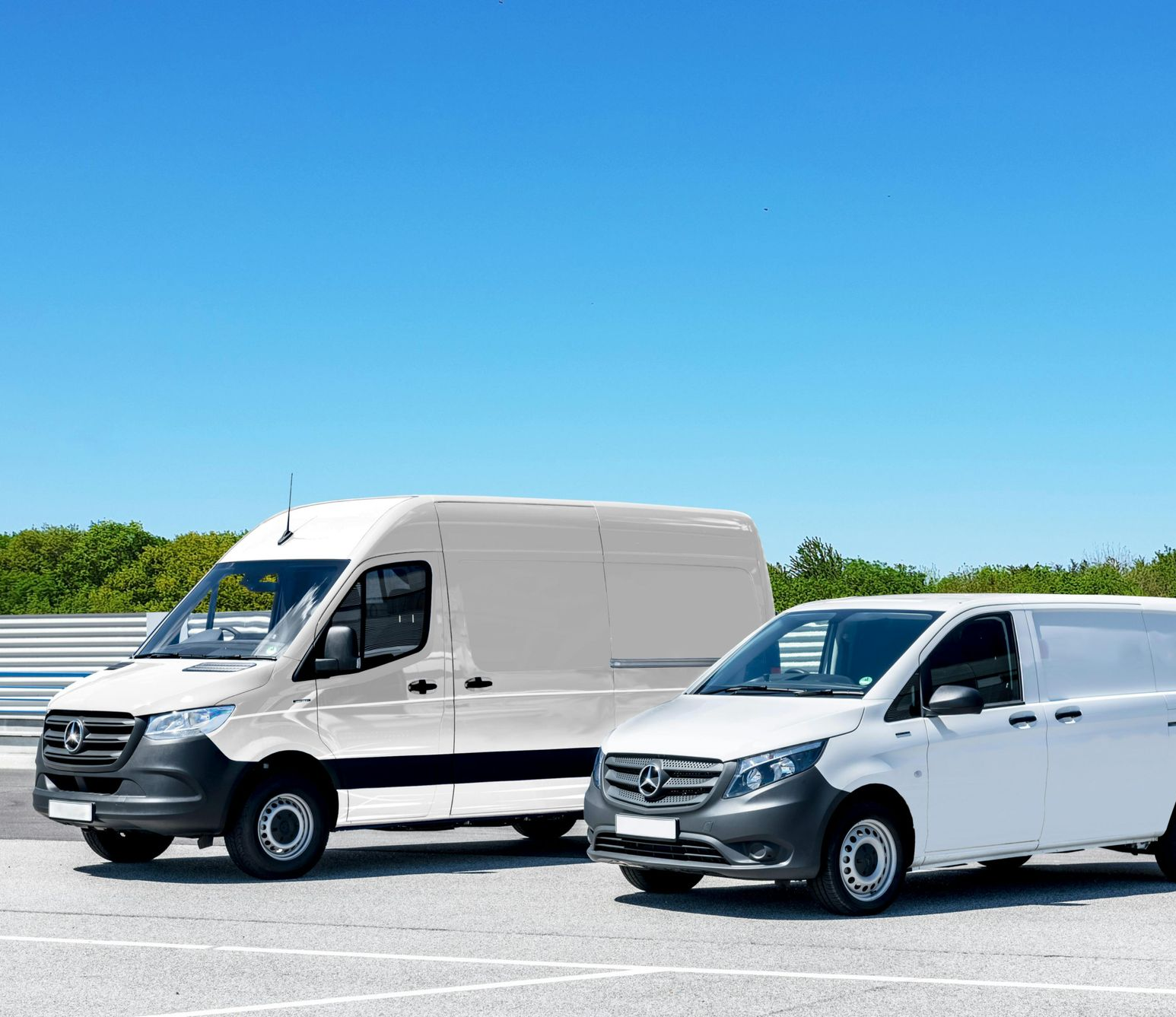 Two white delivery vans parked outdoors on a bright day.