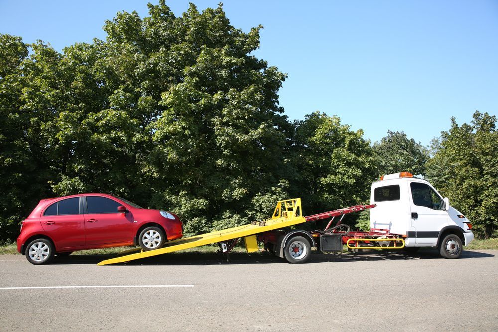 A Red Car is Being Towed by a Tow Truck — Greg Hennessey Smash Repairs In Woolgoolga, NSW