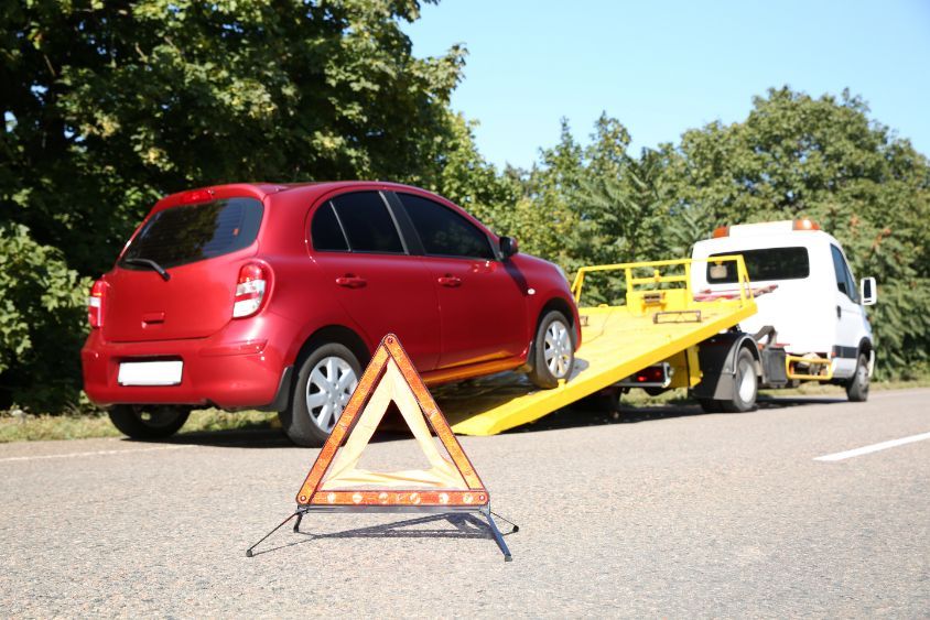 A Red Car is Being Towed by a Tow Truck — Greg Hennessey Smash Repairs In Woolgoolga, NSW
