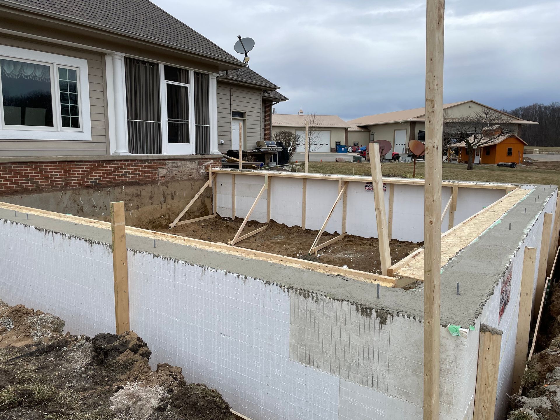 Partially built raised deck beside a house, with timber framing and concrete block foundation.