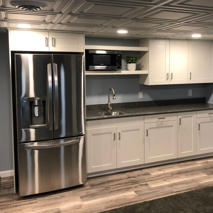 Modern kitchen with stainless steel fridge, sink, microwave, white cabinets, and gray countertops