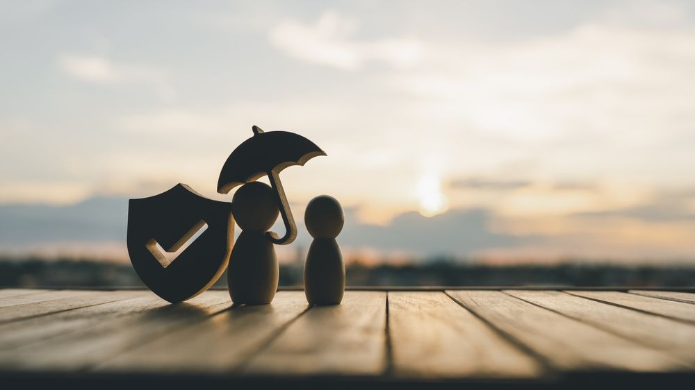 A silhouette of a person holding an umbrella next to a shield on a wooden table.