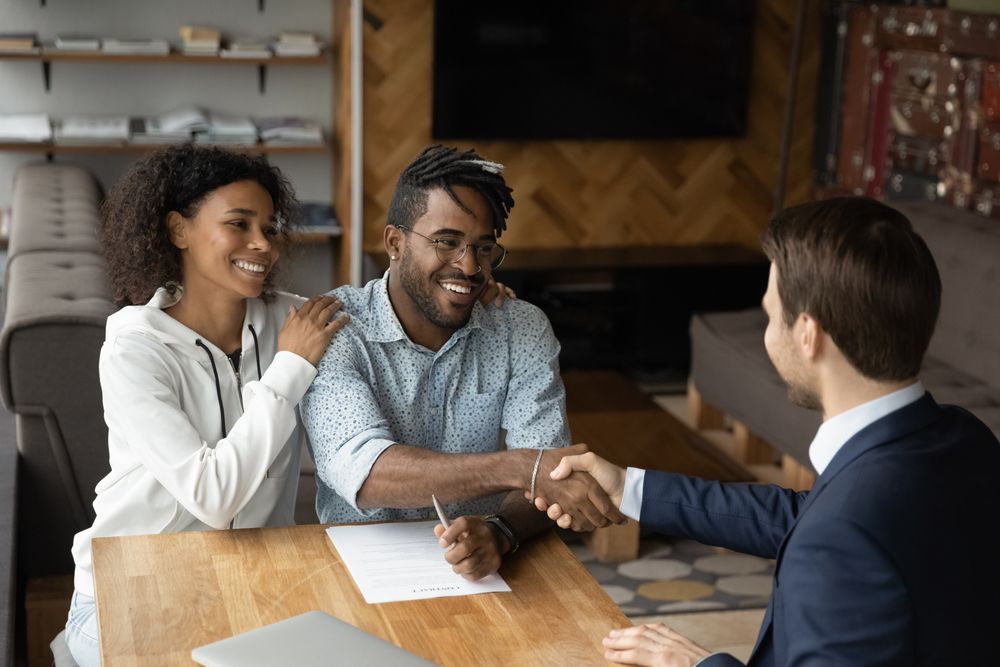 A man and woman are shaking hands with a man while sitting at a table.