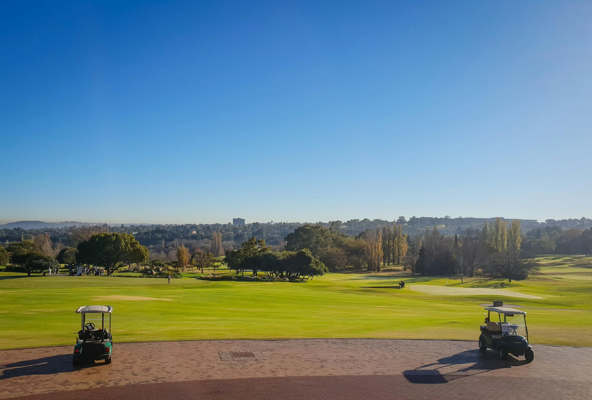 Two golf carts parked on a golf course on a sunny day.